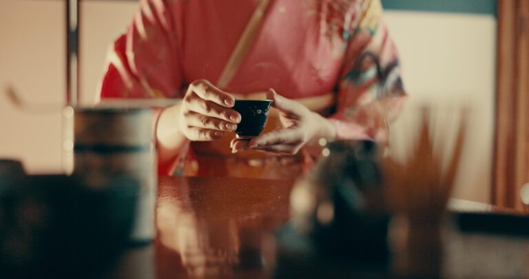 Hands of woman in traditional Japanese tea house, kimono and relax with mindfulness, respect and service. Girl at calm tearoom with matcha drink in cup, zen culture and ritual at table for ceremony